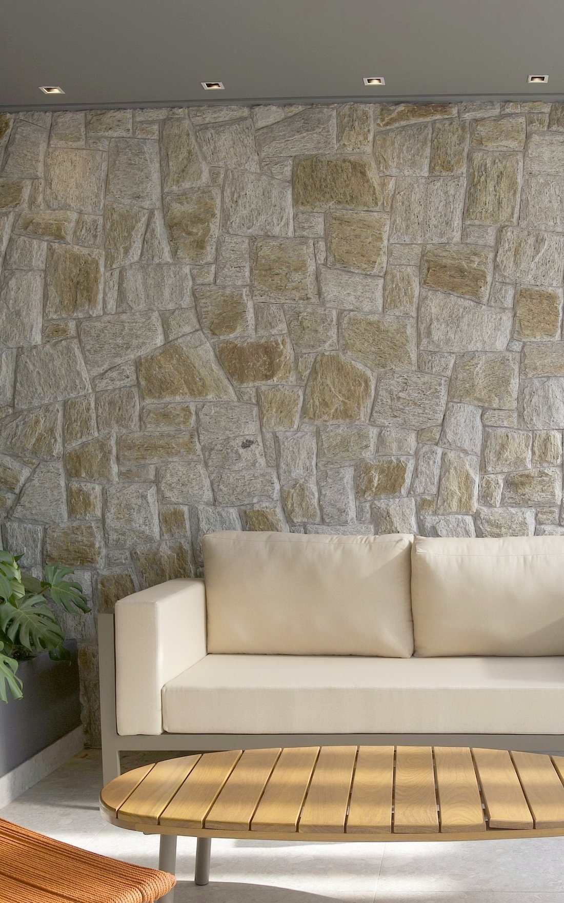 Parede de pedra do lounge, com sofá e mesa de madeira