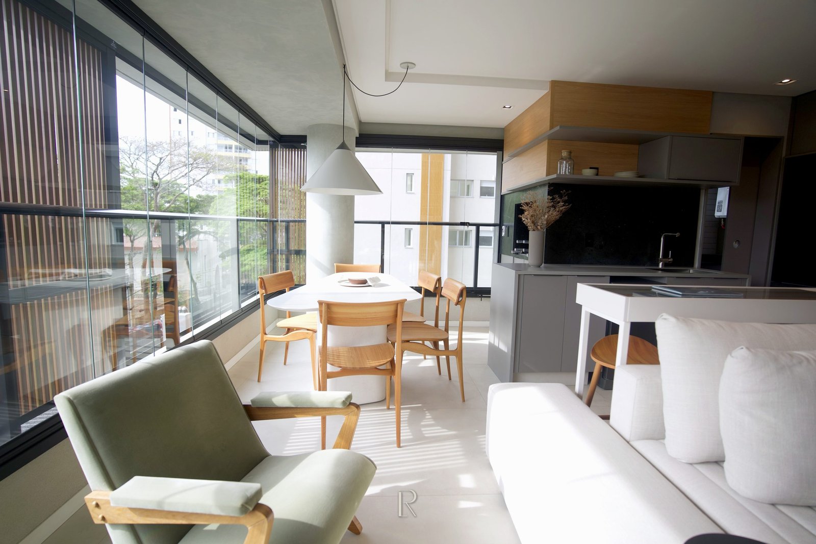 Jantar junto à sacada envidraçada, com a cozinha à direita, no apartamento decorado de 3 dormitórios do Matiss